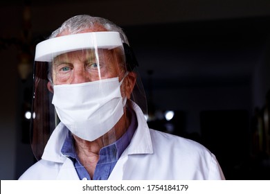 Senior Doctor With Face Mask And Protective Shield, Isolated On Black Background