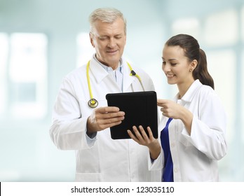 Senior doctor and her assistant standing in the hospital, watching his digital tablet, and discussing reports Stock Photo