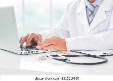 Senior doctor at his office in hospital working close-up using laptop typing - Powered by Shutterstock