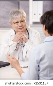 Senior Doctor Listening To Patient In Office, Smiling.?