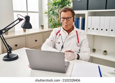 Senior Doctor Man Working On Online Appointment Making Fish Face With Lips, Crazy And Comical Gesture. Funny Expression. 