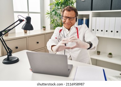 Senior Doctor Man Working On Online Appointment Smiling In Love Doing Heart Symbol Shape With Hands. Romantic Concept. 