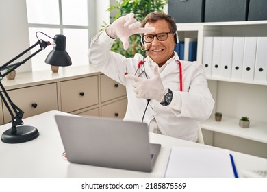 Senior Doctor Man Working On Online Appointment Smiling Making Frame With Hands And Fingers With Happy Face. Creativity And Photography Concept. 