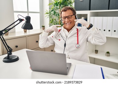 Senior Doctor Man Working On Online Appointment Smiling Cheerful Showing And Pointing With Fingers Teeth And Mouth. Dental Health Concept. 