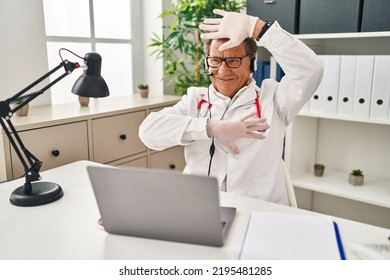 Senior Doctor Man Working On Online Appointment Smiling Cheerful Playing Peek A Boo With Hands Showing Face. Surprised And Exited 