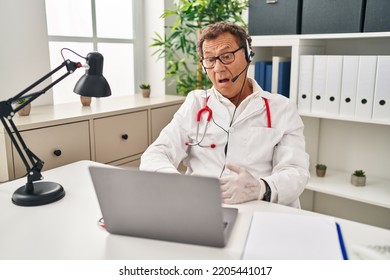 Senior Doctor Man Working On Online Appointment In Shock Face, Looking Skeptical And Sarcastic, Surprised With Open Mouth 