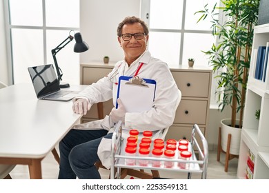 Senior doctor man working with samples looking positive and happy standing and smiling with a confident smile showing teeth  - Shutterstock ID 2253549131