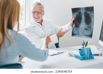 Senior doctor showing xray to his patient in medical office. Pulmonology concept. Coronavirus pneumonia treatment. Cough and flu. Lungs of smoker nonsmoker
