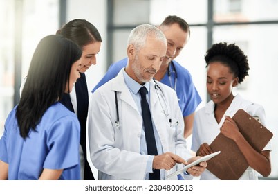 Senior doctor, tablet and coaching intern in healthcare for research, teamwork or meeting at the hospital. Elderly medical professional training staff on technology in team diversity or collaboration - Powered by Shutterstock