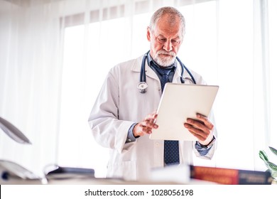 Senior Doctor With Tablet In His Office.