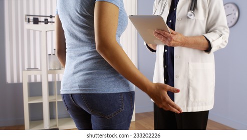 Senior doctor talking with overweight Mexican patient