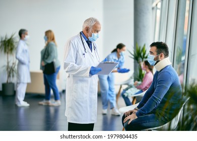 Senior Doctor Talking To Worried Patient Who Has An Injured Neck And Sitting In Waiting Room At Medical Clinic.