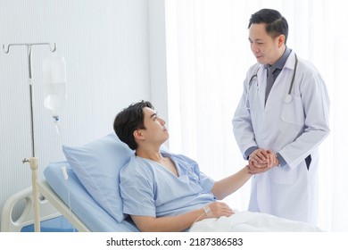 Senior doctor and young male patient who lie on the bed while checking pulse, consult and explain with nurse taking note and supporting in hospital wards. - Powered by Shutterstock