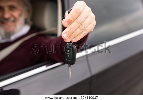 Senior driver is holding\
key of his car