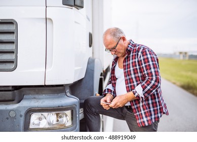 Senior Driver Texting On A Mobile Phone Next To Truck Outdoors.