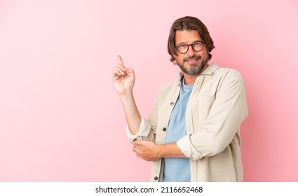 Senior Dutch Man Isolated On Pink Background Happy And Pointing Up