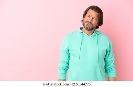 Senior dutch man isolated on pink background having doubts while looking side