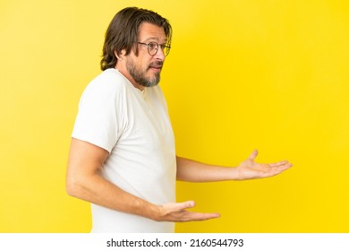 Senior dutch man isolated on yellow background with surprise expression while looking side