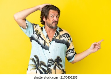 Senior dutch man isolated on yellow background surprised and pointing finger to the side