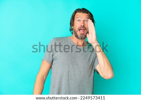 Senior dutch man isolated on blue background shouting with mouth wide open