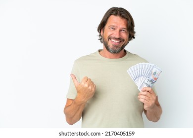 Senior dutch man taking a lot of money isolated on white background pointing to the side to present a product