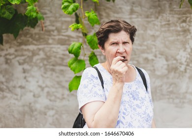 Senior Eating Chocolate Bar Outside - Old Woman Biting A Snack While Looking At The Camera - Healthy Elder Lady Enjoying A Candy