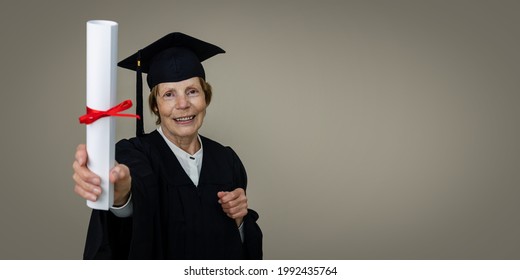 Senior Education - Mature Graduate Woman In Graduation Gown And Cap Showing Diploma. Copy Space