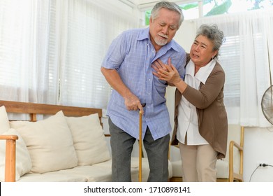 Senior Elder Asian Man Has A Severe Heart Attack Symptom In His House Living Room And Been Take Care By His Wife Suddenly. Senior Health Or Health Care Concept.