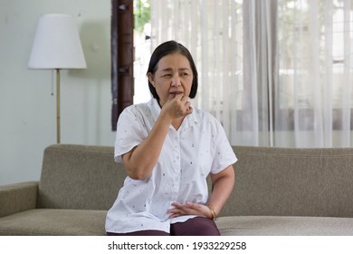 Senior Elderly Asian Woman Taking Medicine While Sitting On Sofa At Home. Older Asian Woman Tanking Pills Medicine. Retirement, Health Care And Ageing Concept