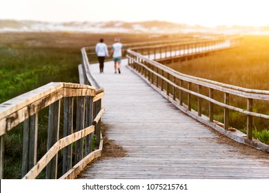 Senior Elderly Couple In Footbridge Walking To Sunset