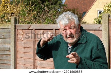 Senior or elderly man lost his temper. Raised fist and pointing. 