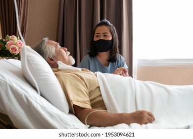Senior elderly man lying on patient bed and woman visiting sitting beside him, holding his hand and hopes for recovery in patient room in the hospital