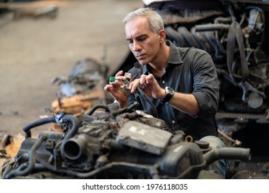 senior engineer checking old used car engine in machinery parts shop warehouse. old technician man Repair vehicle automobile machine in Recycle motor factory