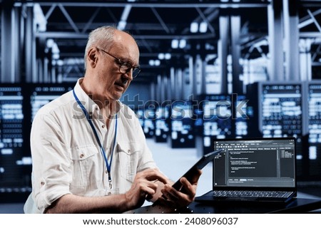 Senior engineer coding in high tech data center using javascript language. Expert updating software on server rigs on laptop terminal, ensuring optimal performance and security