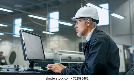 Senior Engineer In Glasses Is Working On A Desktop Computer In A Factory.