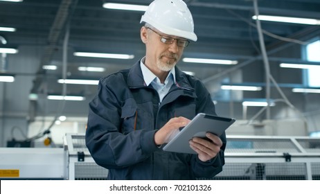 Senior engineer in hardhat is using a tablet computer in a factory. - Powered by Shutterstock