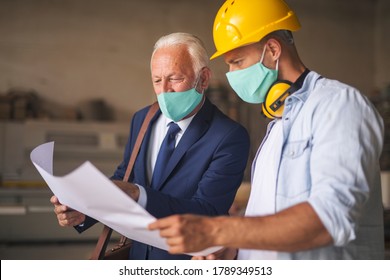 Senior engineer pointing finger at the blueprint trying to explain new project to a carpenter. - Powered by Shutterstock