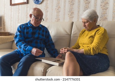 Senior European couple assembling wooden jigsaw puzzle together. Leisure time activities. Active retirement. High quality photo - Powered by Shutterstock