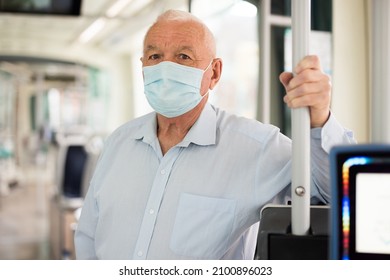 Senior European man in face mask standing inside tram and waiting for his stop. - Powered by Shutterstock
