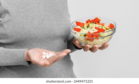 Senior European woman contemplating medication or healthy food on grey background, a s3niorlife decision, cropped - Powered by Shutterstock