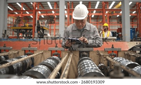 Senior experienced technician checking large machine on a production line at an industrial factory