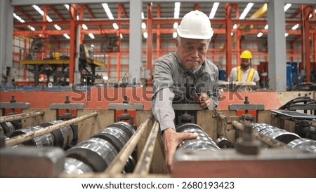 Senior experienced technician checking large machine on a production line at an industrial factory