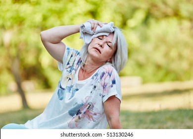 Senior Fainting Woman Holds Wet Cloth On Her Forehead To Cool Down