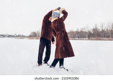 Senior Family Couple Dancing Outdoors During Snowy Winter Weather. Elderly People Having Fun