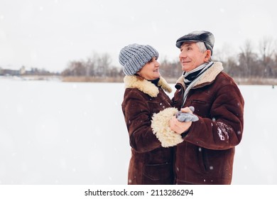 Senior family couple dancing outdoors during snowy winter weather. Elderly people having fun walking. Valentine's day - Powered by Shutterstock