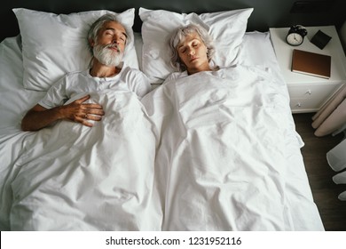 Senior family couple sleeping together in bed.