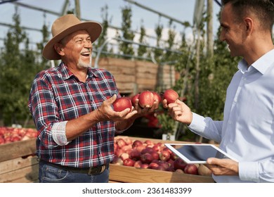 Senior farmer and sales representative talking over digital tablet on apple orchard - Powered by Shutterstock