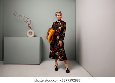 Senior fashion female model standing full length in studio wears black maxi floral dress and socks with shoes. Mature woman with short hair - Shutterstock ID 2277592883