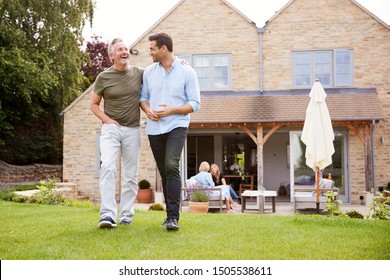 Senior Father And Adult Son Walking And Talking In Garden Together