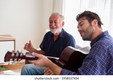 Senior father sing a song and adult son playing guitar on the sofa at home with happy and smile. Elderly father with son play music together on holiday